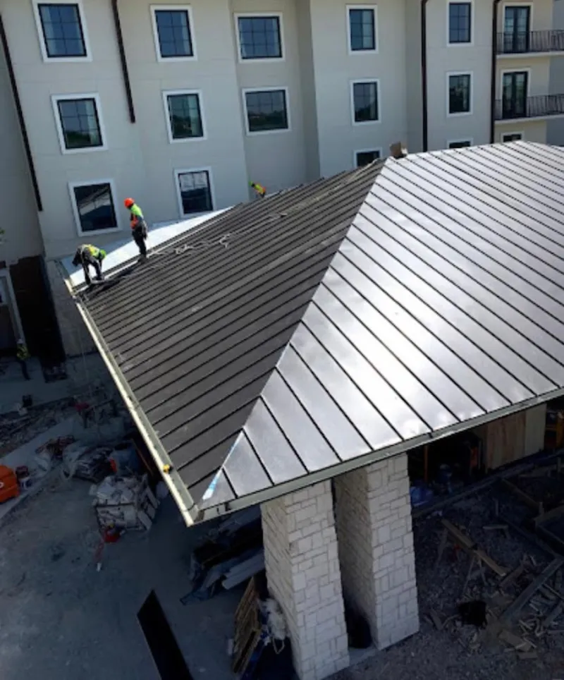 Crew installing standing seam metal roof panels on a commercial project in Avon